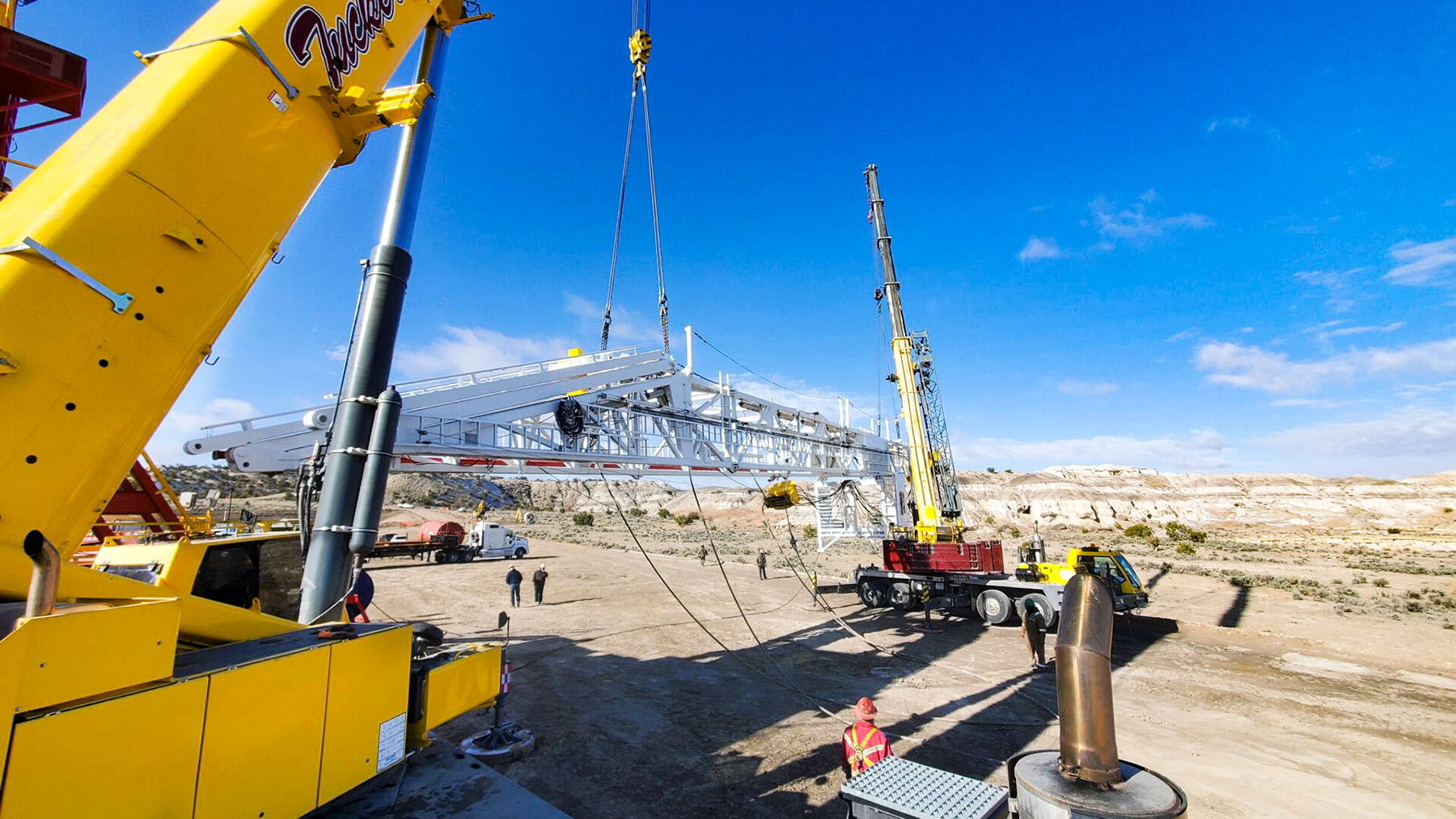 Two cranes lifting large oilfield structure in the badlands near Nageezi, New Mexico
