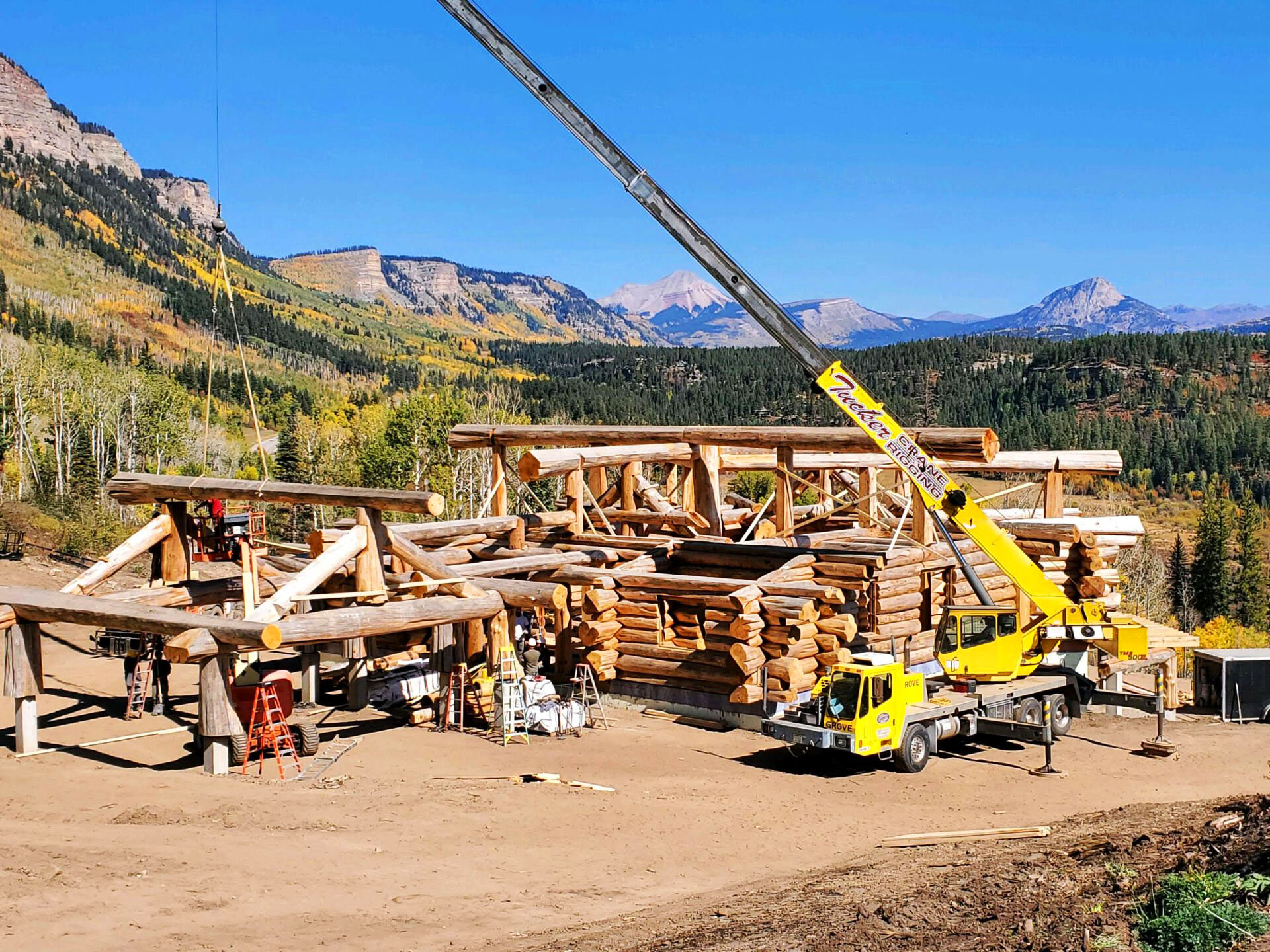 Crane lifting and setting large logs during custom cabin construction in the mountains of Ouray County, Colorado.